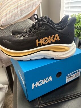 HOKA One One Women's Clifton 10. Size 8B. Black/gold/white. Comes with box.